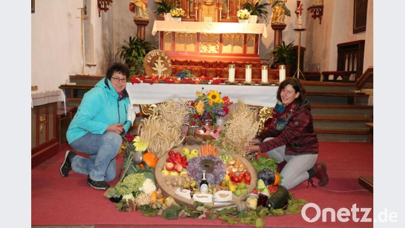 Andrea Zeitler (links) und Martina Schreyer haben die Erntegaben in das „Rad des Lebens“ vor dem Altar aufgebaut. Bild: rpp