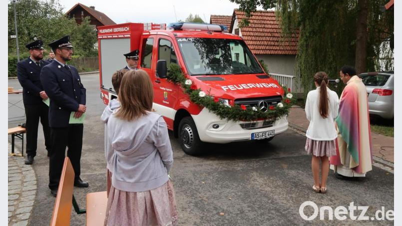Das neue Tragkraftspritzenfahrzeug erhält von Pater Robin Xavier (rechts) den kirchlichen Segen. Auch die Verantwortlichen der Feuerwehr Ebersbach (links neben dem Fahrzeug) bekommen etwas von dem Weihwasser ab. Bild: rab
