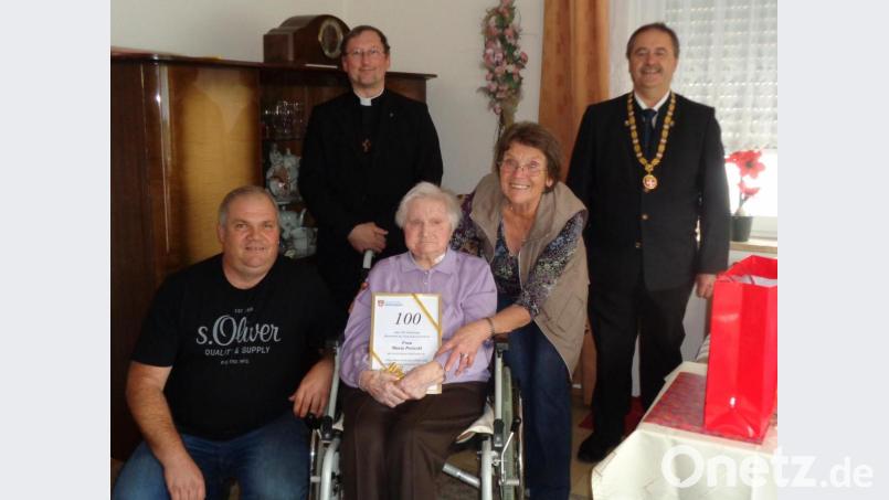 Maria Preischl (Mitte) feiert 100. Geburtstag, hier zusammen mit Enkel Gerhard und Tochter Marianne (vorn), Pfarrvikar Christian Preitschaft (hinten links) und Bürgermeister Peter Dotzler (rechts). Bild: dpe