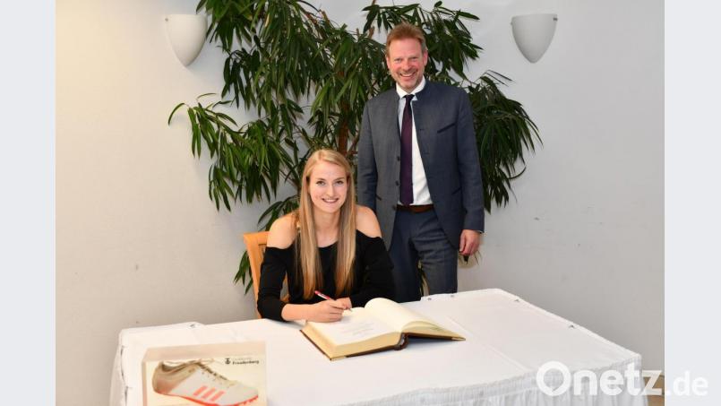 Die deutsche Meisterin über 400 Meter, Corinna Schwab aus Hiltersdorf, trägt sich unter den Augen von Bürgermeister Alwin Märkl in das Goldene Buch der Gemeinde Freudenberg ein. Bild: sche