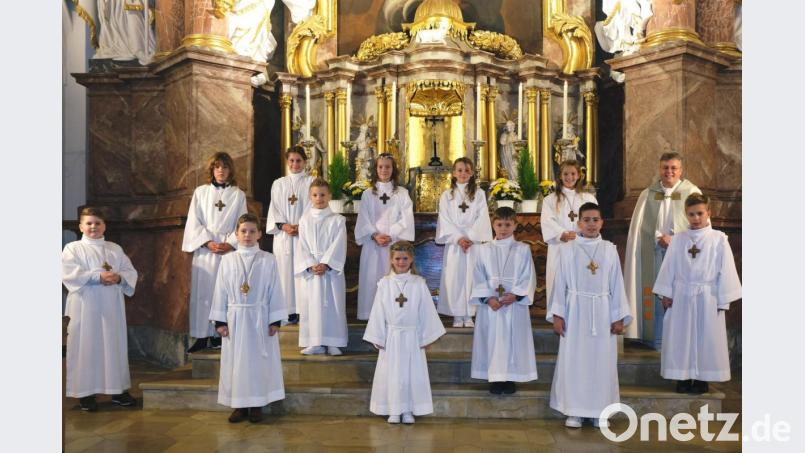 Auf den Stufen zum Hochaltar der Pfarr- und Klosterkirche stellen sich die zwölf Erstkommunionkinder mit Ortspfarrer Prior Adrian Kugler zu einem Erinnerungsfoto auf. Bild: do