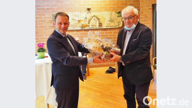 Oberbürgermeister Jens Meyer (links) überreicht das Abschiedsgeschenk für den scheidenden Seniorenbeauftragten Alfons Heidingsfelder. Bild: Bühner
