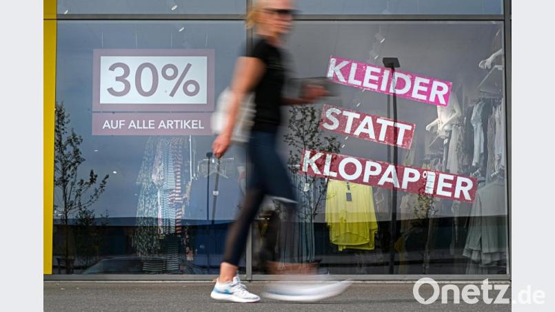 Eine Frau geht am Schaufenster eines Modegeschäfts vorbei, auf dem steht &quot;30 Prozent auf alle Artikel&quot; sowie &quot;Kleider statt Klopapier&quot;. Werbung spielt oft mit Klischees. Bild: Felix Kästle/dpa