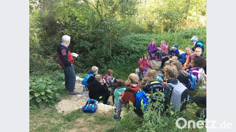 An der Peuteltalquelle erzählt Werner Luber den Schulkindern über das im Volksmund sogenannte „Beindohlmandl“, das einst hier sein Unwesen getrieben und Leute erschreckt haben soll. Bild: gru
