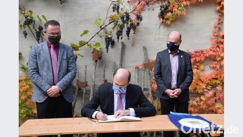 Für den Bayerischen Finanzminister Albert Füracker gehört der Eintrag ins Goldene Buch des Marktes dazu. Bürgermeister Florian Junkes (links) und LBV-Vorsitzender Norbert Schäffer freuen sich über das Lob darin zum Fledermaushaus. Bild: bö