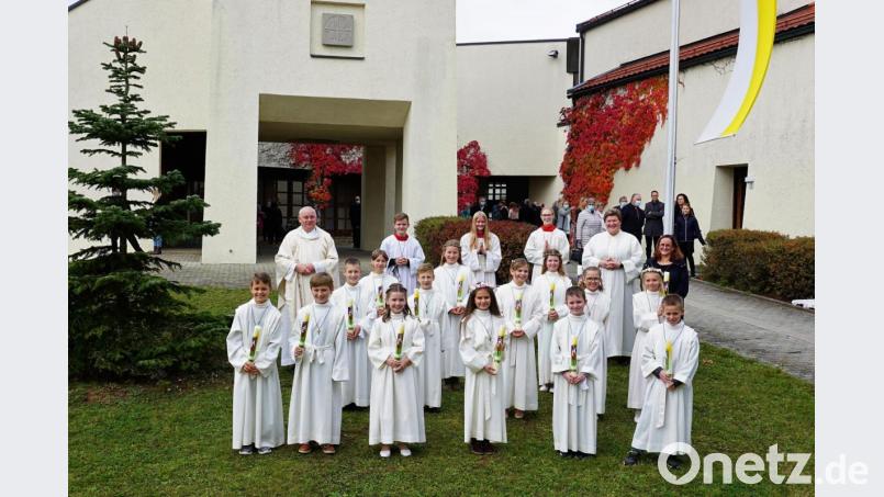 Pfarrer Herbert Grosser (hinten links) mit den 14 Erstkommunionkindern, Gemeindereferentin Kathrin Blödt (hinten, Zweite von rechts), Lehrerin Ulrike Erlbacher (rechts) und den Ministranten vor der Bruder-Konrad-Kirche. Bild: wec