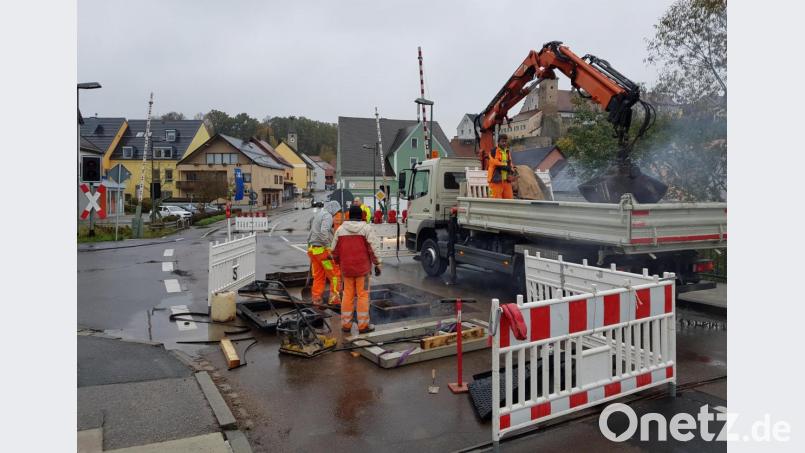 Straßenarbeiter der oberfränkischen Firma OFM erneuern am Nabburger Bahnübergang die defekte Schachtabdeckung der Telekom. Im mehrere Meter tiefer gelegenen Hohlraum darunter verlaufen Telefon- und Internetkabel. Bild: Tobias Gräf