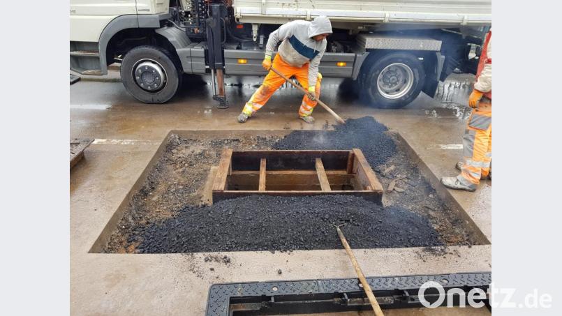 Die Arbeiter füllen die sogenannte Grobkörnung als Tragschicht um den Schachtrand. Später wird darüber der Feinasphalt passgenau aufgetragen. Bild: Tobias Gräf