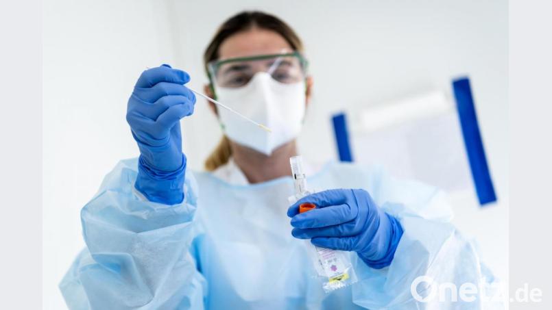 Eine Krankenschwester steckt eine Probe mit einem Nasenabstrich eines Patienten, der auf das neuartige Coronavirus getestet wird, in einen Behälter. Symbolbild: Jean-Christophe Bott/KEYSTONE/dpa