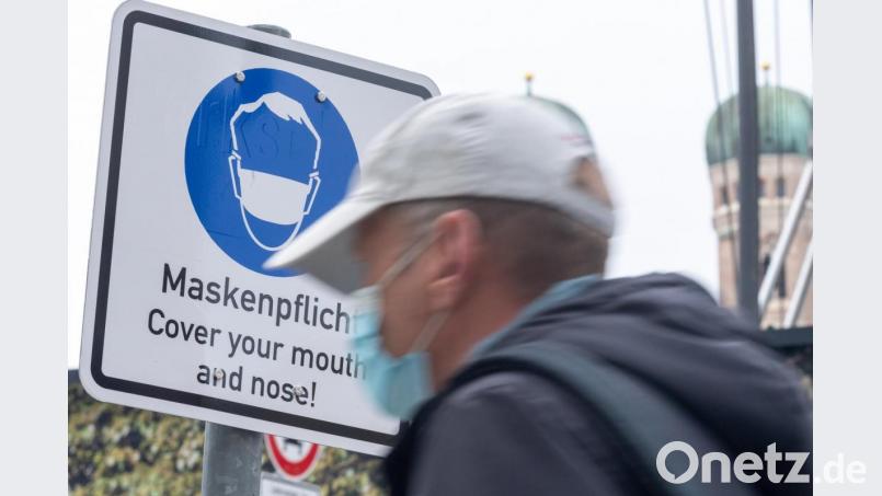Ein Passant geht an einem Schild vorbei, das auf das Tragen einer Maske hinweist. Bild: Peter Kneffel/dpa