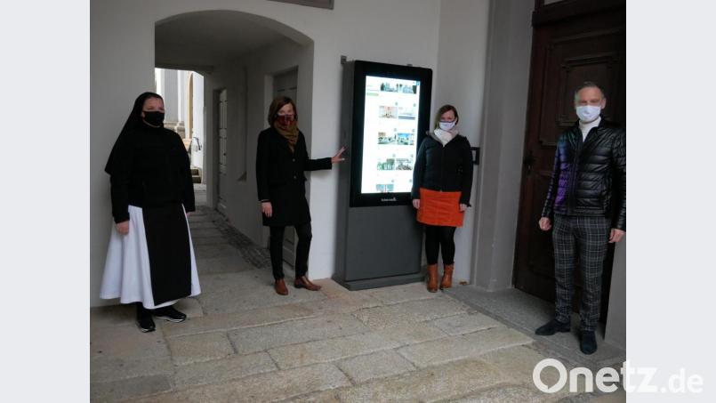 Schwester Sophia Schlembach, Inge Frank von der Tourist-Info, Belinda Hoyer von der Ferienregion Stiftland und Bürgermeister Bernd Sommer stellten die neue digitale Informationsstele im Durchgang von der Basilika zum Klosterhof vor. Bild: hmr