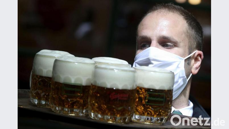 Ein Kellner mit Maske trägt Bier auf einem Serviertablett (Symbolbild): In Amberg haben sich vor dem Lockdown nicht alle Wirte an diese und weitere Corona-Vorschriften gehalten. Symbolbild: Ronald Zak/dpa