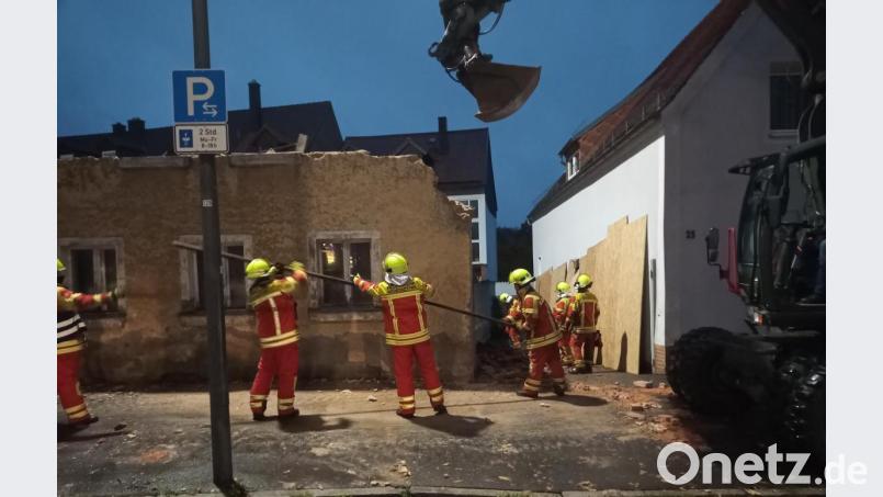 Mit den Händen unterstützten die Feuerwehrleute den Notabriss des alten, maroden Hauses in der Freyung, nachdem der Dachstuhl eingeknickt war. Bretter schützen das Nachbaranwesen. Bild: Feuerwehr Neustadt/exb