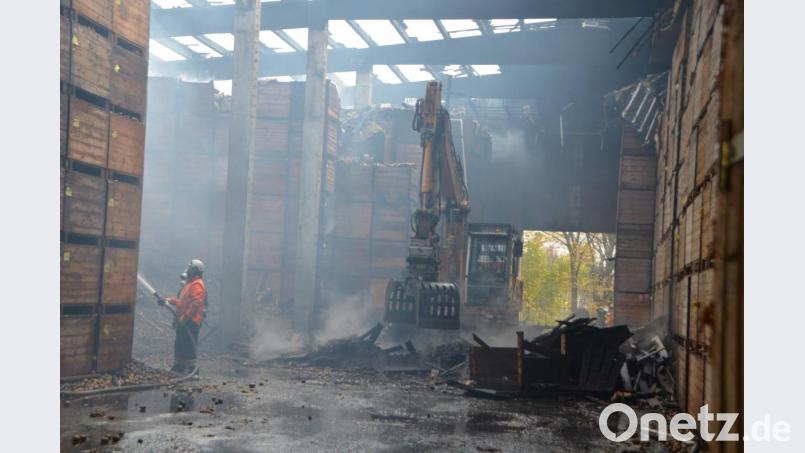 Während Feuerwehrleute die Kartoffeln noch bewässern, ist ein Bagger damit beschäftigt, die Kistenstapel auszuräumen. Bild: dob