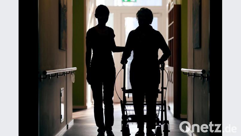 Eine Pflegekraft begleitet die Bewohnerin eines Altenheims mit Rollator beim Gang über den Flur. Symbolbild: Oliver Berg