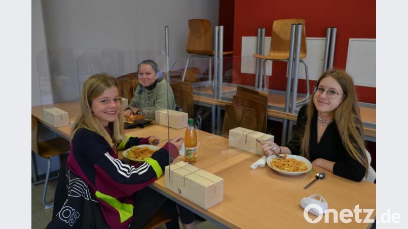 Marlene Züllich, Natalie Brandl und und Alina Grüner (von links) machen in der Mensa des Stiftland-Gymnasiums Mittagspause. Sie sind durch Plexiglasscheiben getrennt. Bild: kaz