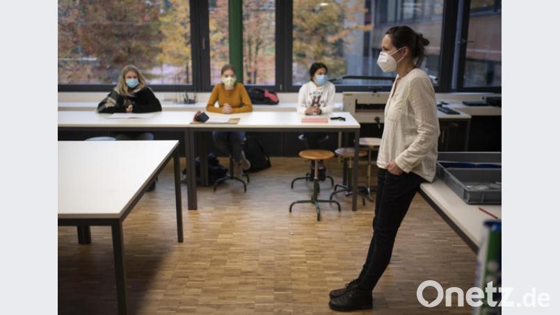 Eine Lehrerin mit einer Schutzmaske steht vor einer Schulklasse, in der die Schülerinnen einen Mund-Nasen-Schutz tragen. Das könnte bald flächendeckend angeordnet werden. Bild: Gian Ehrenzeller/dpa
