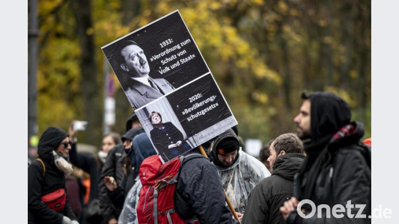 Verqueres Demokratieverständnis: Ein Teilnehmer der Demonstration gegen die Corona-Einschränkungen hält ein Schild hoch auf dem Angela Merkel mit unter Adolf Hitler gleichgesetzt wird. Bild: Fabian Sommer/dpa