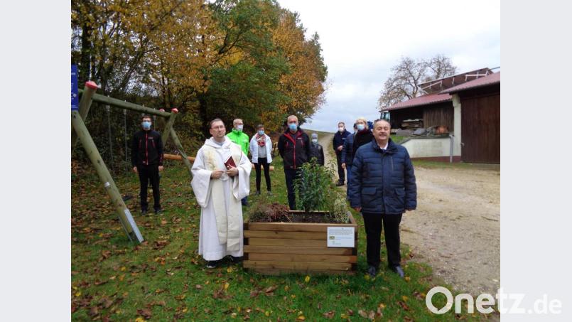 Pfarrvikar Christian Preitschaft (links) segnet den sanierten Kinderspielplatz in Atzmannsricht, hier zusammen mit dem Gebenbacher Bürgermeister Peter Dotzler (rechts), Ortsvorsteher Werner Kohl (Mitte), einigen Gemeinderäten sowie Bürgern im Hintergrund. Bild: dpe
