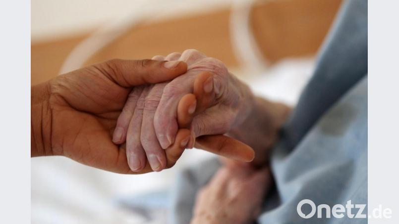 Eine Pflegerin hält im Altenheim die Hand einer Bewohnerin. Bild: Oliver Berg/dpa