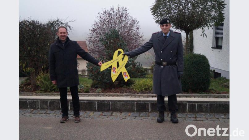 Hauptmann Matthias Forster (rechts) überreicht die gelben Schleifen an Bürgermeister Josef Pretzl. Bild: sgs