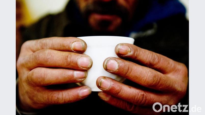 Ein obdachloser Mann hält in einem Nachtcafé seine Tasse. Bild: Sebastian Kahnert/dpa