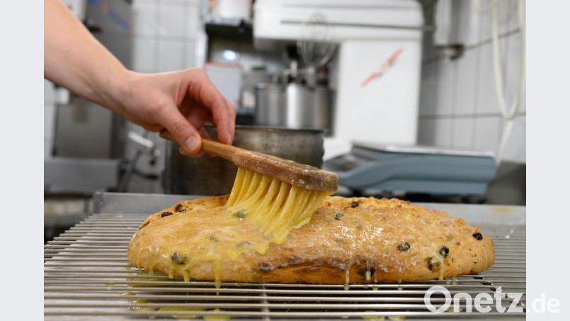 Ein Bäcker bestreicht einen Stollen mit geschmolzener Butter. Symbolbild: Sebastian Kahnert/dpa