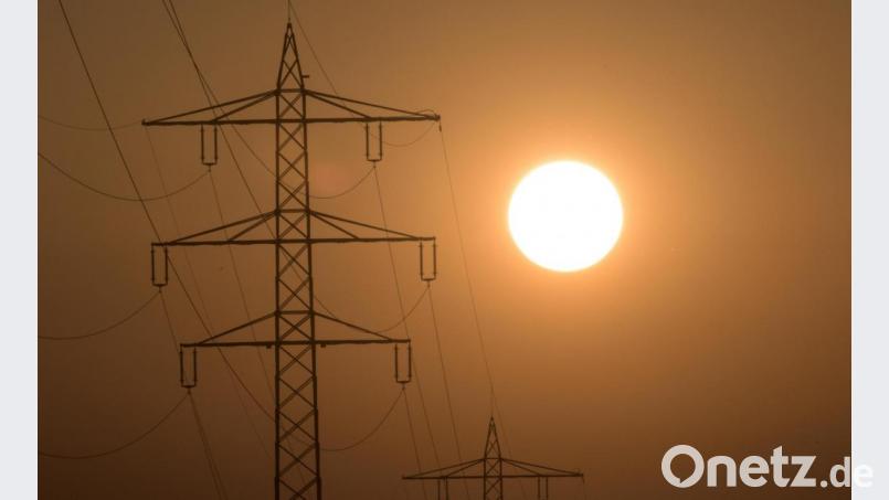 Die Sonne geht hinter einem Strommasten unter. Bild: Patrick Seeger/dpa
