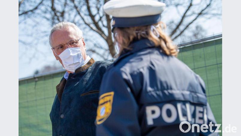 Der bayerische Innenminister Joachim Herrmann (CSU) spricht mit einer Polizistin - natürlich mit Mund-Nasen-Schutz. Bild: Lino Mirgeler