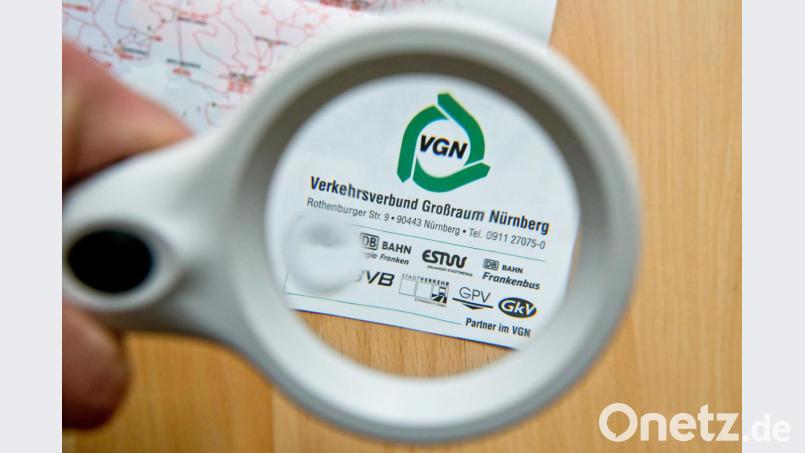 Durch eine Lupe ist auf einer Karte des Verkehrsnetzes des Verkehrsverbund Großraum Nürnberg (VGN) das VGN-Logo zu sehen. Amberg-Sulzbach ist hier ab 1. Januar voll integriert. Bild: Daniel Karmann/dpa