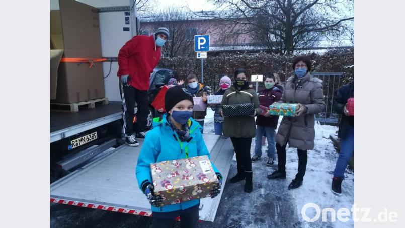 An ehrenamtliche Mitarbeiter von Humedica überreichen Schüler der Klasse 4c und Rektorin Eva Hampel die Weihnachtspäckchen. Bild: hmp