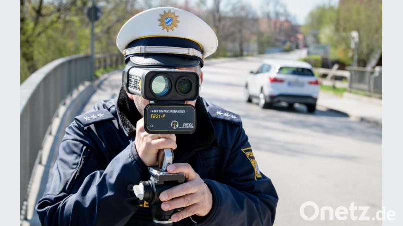 Ein Polizist misst die Geschwindigkeit vorbeifahrender Fahrzeuge mit einer Laserpistole. Symbolbild: Matthias Balk/dpa