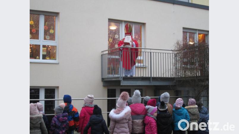 Von der Außenanlage aus verfolgten die Mädchen und Buben des Kindergartens St. Hedwig den Besuch des Nikolaus. Dieser war auf den Balkon des Gebäudes getreten, um zu den Kindern zu sprechen. Bild: Kerstin Pflaum/exb