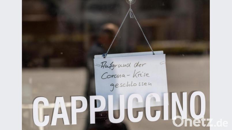 Ein Schild mit der Aufschrift «Aufgrund der Corona-Krise geschlossen» hängt in der Tür zu einem Cafe in der Innenstadt von München. Bild: Peter Kneffel/dpa