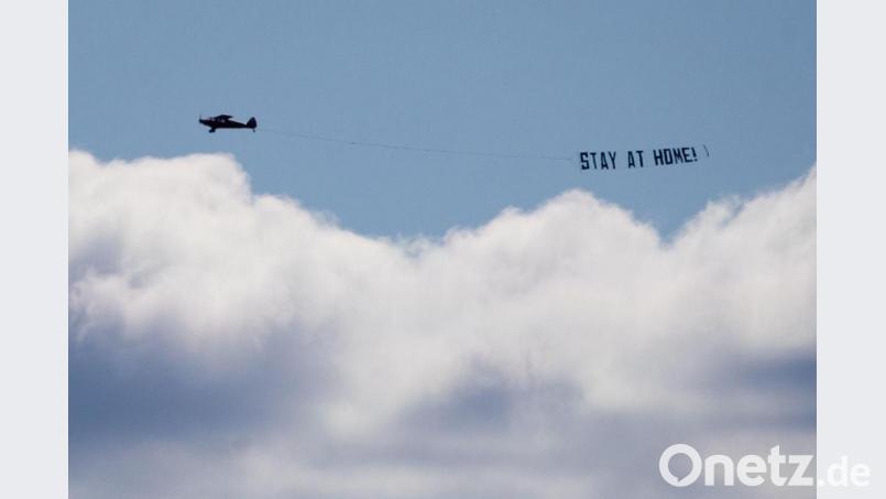 Ein kleines Flugzeug fliegt mit einem Banner mit der Aufschrift «Stay at Home!» : Im Kreis Amberg-Sulzbach ist das inzwischen kein Appell mehr, sondern eine neue Corona-Maßnahme in Form einer nächtlichen Ausgangssperre. Symbolbild: Christian Charisius