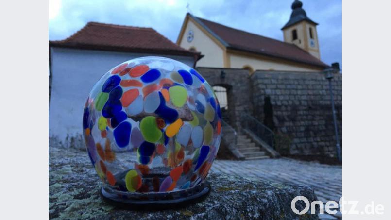 So sieht er aus, der Preis: Ein Stein vom Johannisberg, umgeben von einer kunstvollen, bunten Glashülle. Im Hintergrund die Wutschdorfer Pfarrkirche St. Martin. Bild: ads