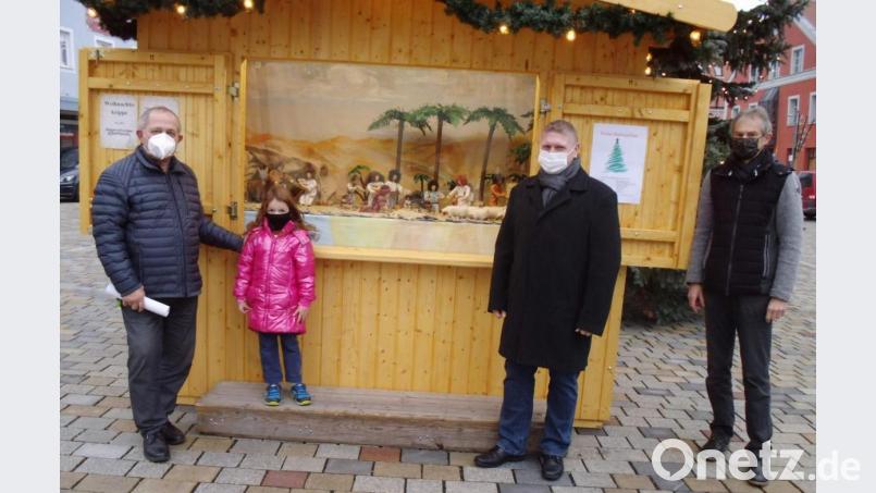 Auf dem Hirschauer Marktplatz steht ein Markthäuschen, in der eine Krippe mit Regensburger Bibelfiguren steht. Die Idee dazu hatte Günther Siegert (rechts), der Vorsitzende der Elterninitiative Eltern für Kinder, der alljährlich den Weihnachtsmarkt organisiert. Unterstützt wurde er von Martin Merkl (Zweiter von rechts), der in jedem Jahr für die Krippenausstellung verantwortlich zeichnet. Zur Verfügung gestellt haben die Figuren Bärbel und Reinhold Birner (links), hier mit seiner Enkelin Mathilda. Bild: u