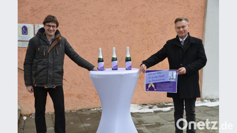 Der evangelische Stadtpfarrer Dieter Schinke (rechts) wirbt mit Uli Münchmeier aus dem Kirchenvorstand für die Sekt-Aktion zugunsten der renovierungsbedürftigen Stadtkirche. Bild: dob