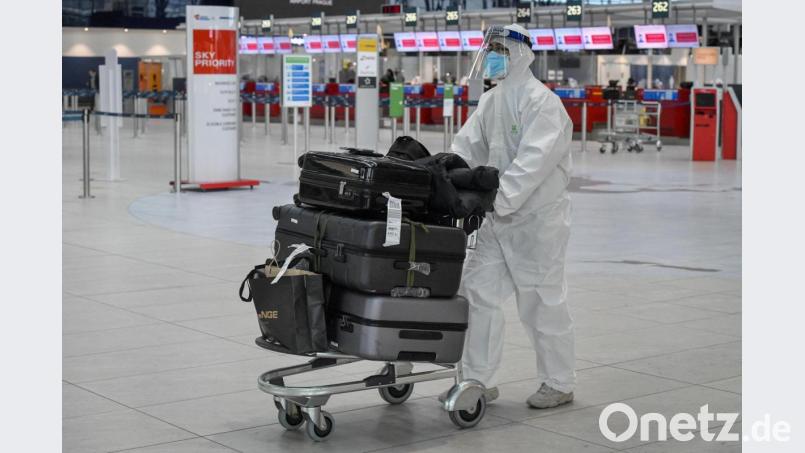 Ein Passagier, der zum Schutz vor dem Coronavirus einen Schutzanzug, Mund-Nasen-Schutz und Gesichtsvisier trägt, schiebt einen Gepäckwagen durch die Abflughalle des Flughafens Prag. Bild: Vít Šimánek