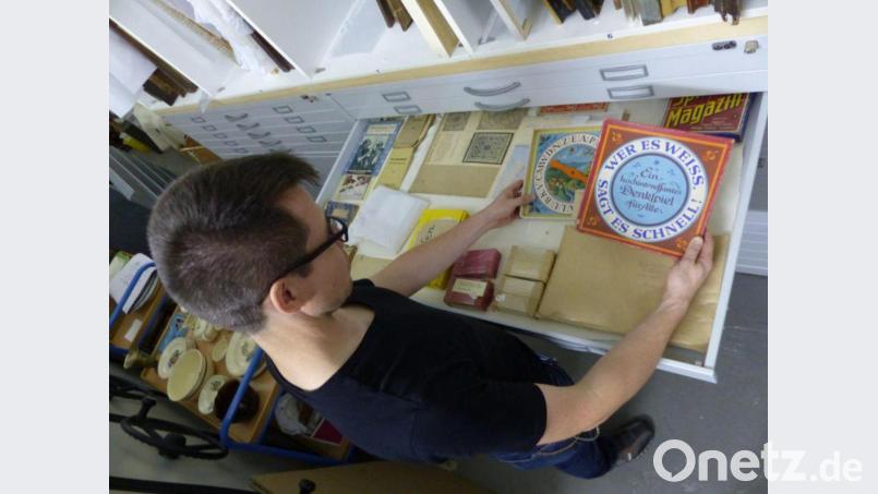 Museumsmitarbeiter Simon Steiner bei der Arbeit im Außendepot im Keller des Verwaltungsgebäudes der Verbandskläranlage. Er sortiert Museumsobjekte in einen Grafikschrank ein. Bild: Simon Steiner/exb