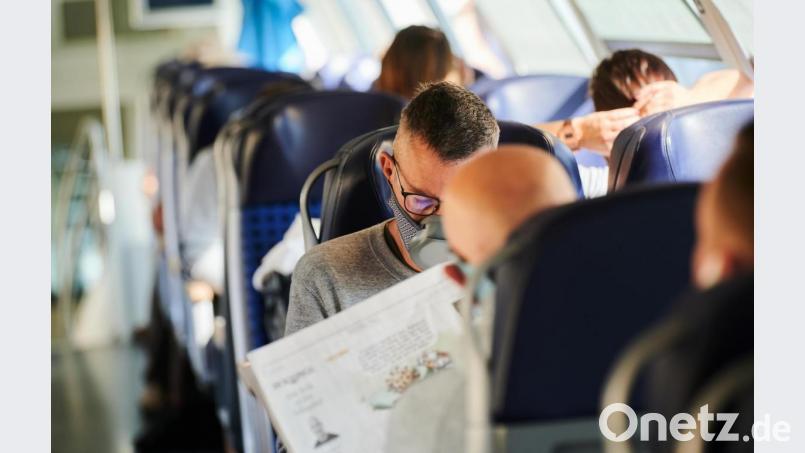 Reisende sitzen mit Nasen-Mund-Schutz in einem Zug. Bild: Annette Riedl/dpa