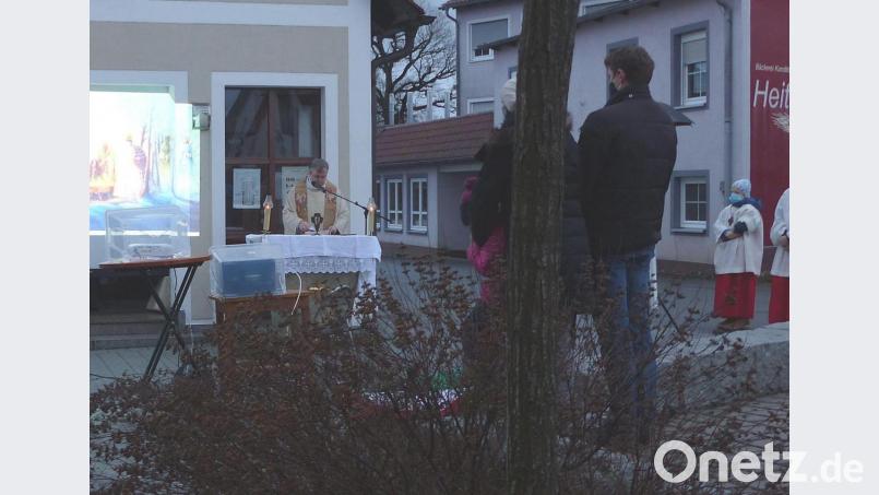 Auf dem Vorplatz der Pfarrkirche feiert Pater Adrian Kugler mit den Familien die Kindermette. Auf einer Leinwand wird die Weihnachtsgeschichte gezeigt. Bild: lgc