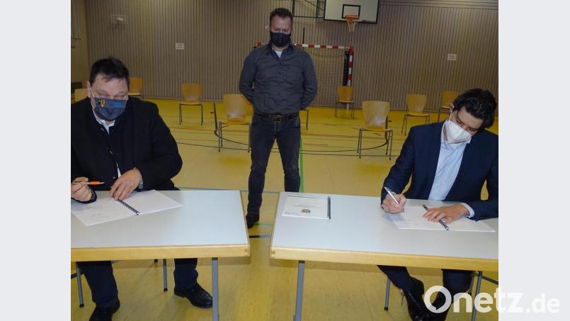 Unterschrift in der Turnhalle: Bürgermeister Christian Ziegler (links) und Amplus-Vorstand Martin Naber (rechts) setzten ihre Namen auf einen Kooperationsvertrag zum Breitbandausbau in Freihöls. Zwischen beiden Eduard Maier von der Breitbandberatung Bayern. Bild: Houschka