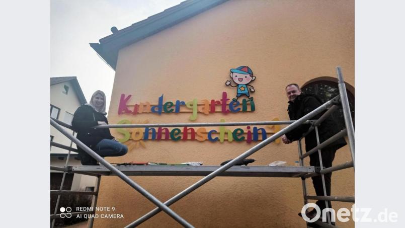 Das neue Schild an der Fassade des Kindergarten Sonnenschein in Ebermannsdorf wird angebracht. Bild: exb