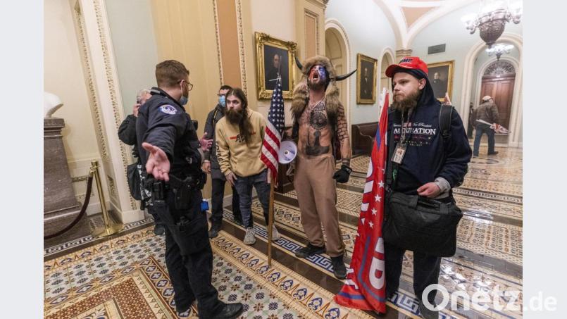 Unterstützer von US-Präsident Trump stehen vor Polizeien auf dem Gang vor der Senatskammer im Kapitol. Bild: Manuel Balce Ceneta/dpa