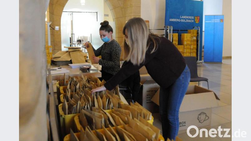 Anna-Lena Hörl (links) und Julia Christl sind zwei der fleißigen Helfer im Landratsamt, die derzeit Masken und Anschreiben in Kuverts verpacken und die Briefe an besonders bedürftige Menschen im Landkreis Amberg verschicken. Bild: Christine Hollederer