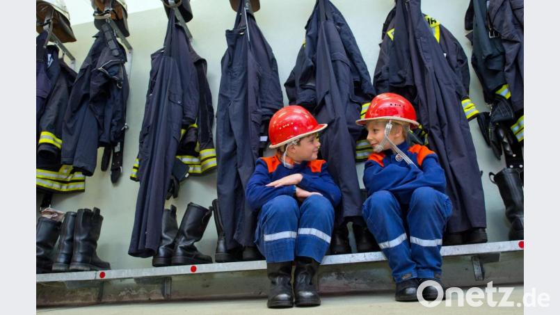Zwei Achtjährige sitzen in ihrer Kinder-Uniform in einem Feuerwehr-Gerätehaus (Symbolbild). Die Schnaittenbacher Wehr bekommt auch eine Kindergruppe, aber die kann erst gegründet werden, wenn es die Pandemie zulässt. Symbolbild: Patrick Pleul/dpa
