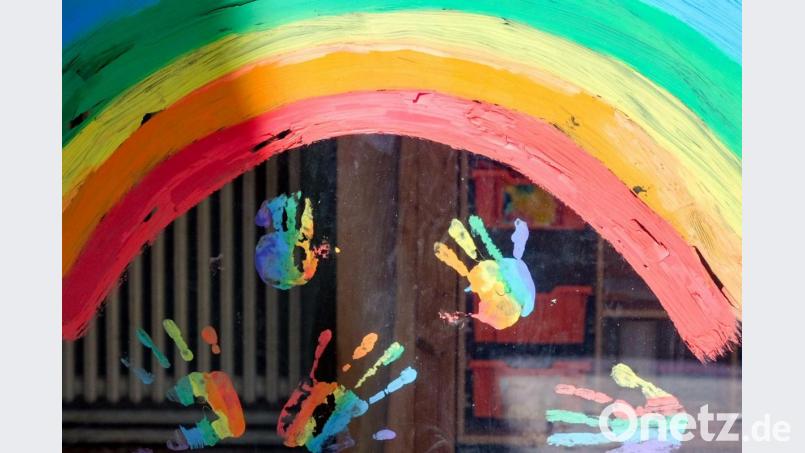 Kinderhände und ein Regenbogen sind an einer Kita zu sehen. Symbolbild: Jens Kalaene/dpa