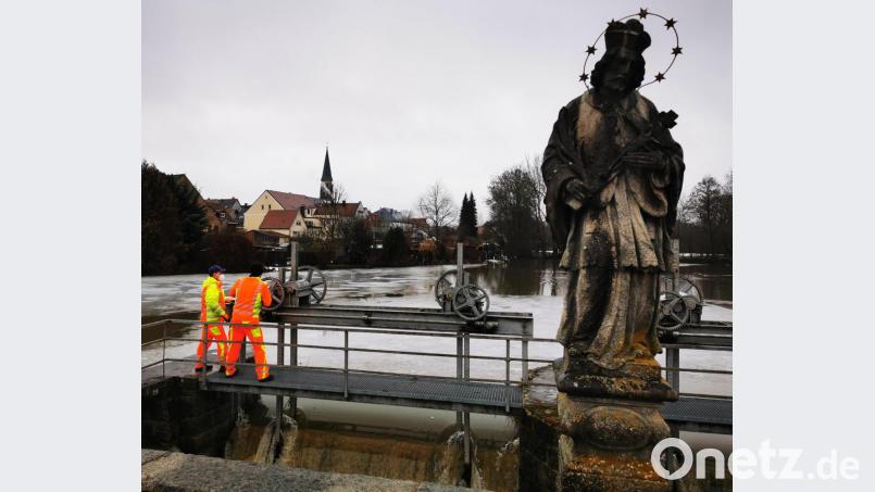 Ein Imposantes Bild. Die Statue des Hl. Nepomuk, dem Brückenheiligen mit dem Wehr des Stadtweihers, dahinter dem Kemnather Kirchturm und den reißenden Wassermassen am Wehr, welche in den Fallbach stürzen. Bild: mde