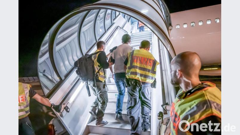 Polizeibeamte begleiten einen Flüchtling, der abgeschoben werden soll, in ein Charterflugzeug. Archivbild: Michael Kappeler